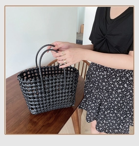 Close-up of black woven hollow tote bag featuring sturdy round double handles for beach use
