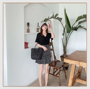 Close-up of a stylish black woven tote bag styled with a summer floral skirt outfit