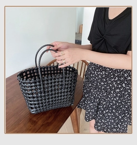 Detail of hand-woven black hollow mesh beach bag with minimalist rounded handles
