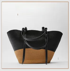 Close-up of color-blocked straw tote bag with black leather handles and white stitching