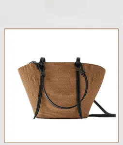 Detail of handwoven straw bucket bag with black leather straps and white contrast stitching