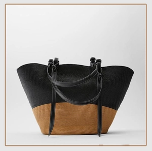 Detail of color-block straw tote showing black leather straps with white contrast stitching