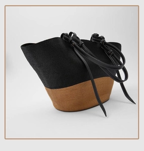 Detail of color-block straw tote bag with black stitching on leather straps
