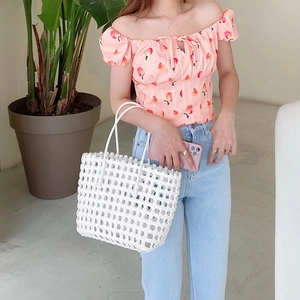 Handwoven hollow white beach bag styled with a summer floral top and jeans