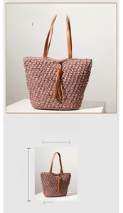 Detail view of pink straw tote bag with brown leather handles and tassel accents