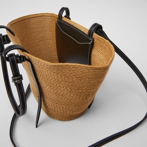 Handmade woven straw basket bag with leather accents and internal pocket for beach vacation