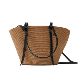 Handwoven straw tote bag with brown texture and black leather straps for beach holidays