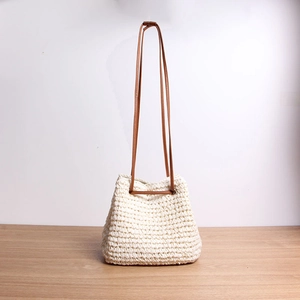 Close-up of handmade straw bucket bag with cotton rope weaving and brown leather strap