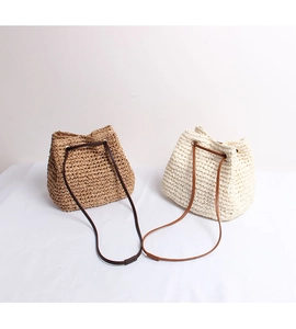 Close-up of hand-woven straw bucket bags with leather drawstring straps for summer beach