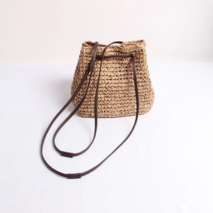 Minimalist straw woven bucket bag in natural wood color with brown drawstring strap