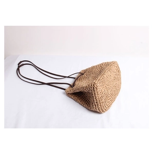 Detail of hand-woven straw shoulder bag texture with slim faux leather straps for summer