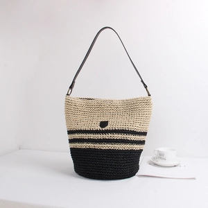 Minimalist straw bucket bag with black and beige striped pattern and leather shoulder strap