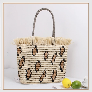 Close-up of straw woven tote with leopard pattern accents and decorative fringe trim