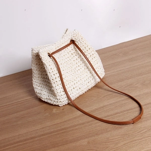 Chic woven straw crossbody bag in beige with brown leather strap for beach vacations