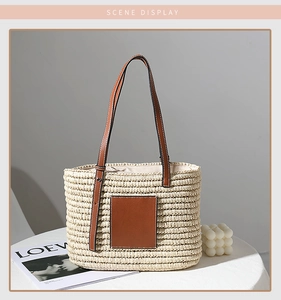 Detail of handmade straw tote bag featuring brown leather straps and square patch accent