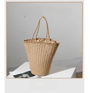 Macro shot of hand-woven straw tote bag with scalloped edge detail on white pedestal