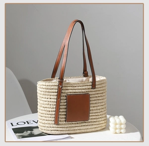Detail of hand-woven straw tote bag with brown leather handles on white round table