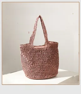 Close-up of hand-woven straw tote bag in dusty rose with detailed crochet texture