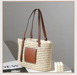 Detail of square woven straw tote with leather handles and drawstring lining on table