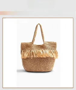Detail of woven straw tote bag featuring natural fibers and decorative raffia tassels