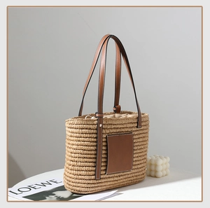 Close-up of handmade square straw tote bag with brown leather straps and drawstring closure