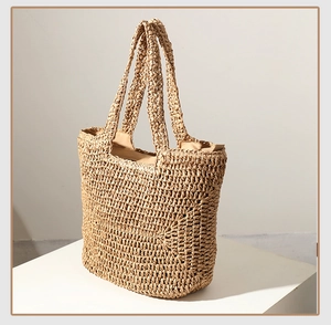 Detailed close-up of woven straw texture and dual shoulder straps on a beige tote bag