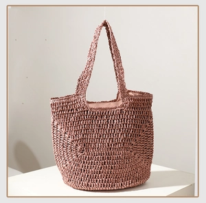 Detail of handwoven straw tote in dusty pink with textured surface for beach use