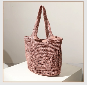 Detail of dusty rose straw woven handbag with textured knit pattern and round handle