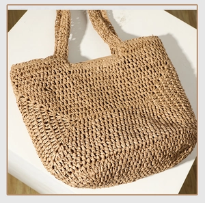 Detail of hand-woven straw tote bag showing thick texture and dual top handles