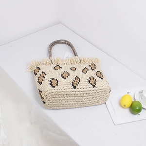 Fashionable straw tote bag with leopard pattern and tassel details on white background