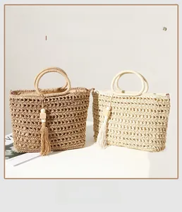 Close-up of handwoven hollow texture and wooden bead tassel on straw tote bags