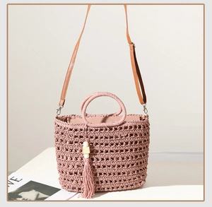 Detail of hollow-out woven texture on pink straw bag with wooden bead tassel and PU strap