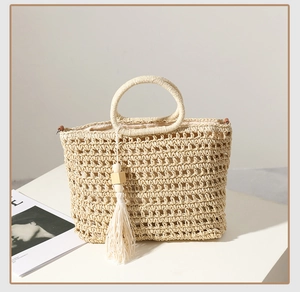 Detailed close-up of beige straw bag showing hollow weave texture and wood bead tassel