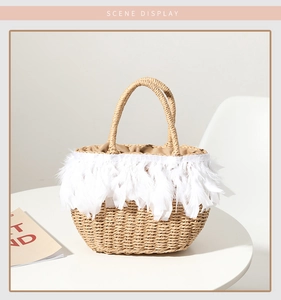 Detail of hand-woven straw bag featuring delicate white feather trim and round handles