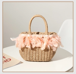 Detail of hand-woven straw bag featuring delicate pink feather trim and drawstring lining