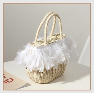Close-up of woven straw handbag featuring elegant white feather trim and fabric drawstring liner