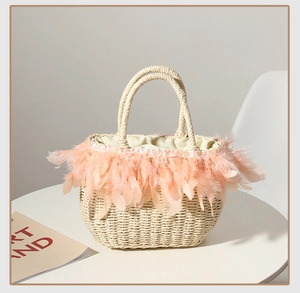 Detail view of woven straw tote bag featuring delicate light pink feather trim accents
