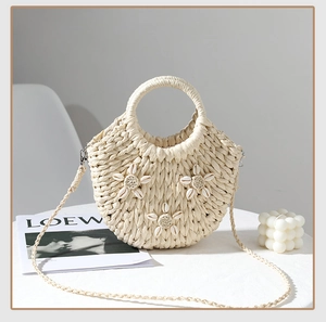 Dettaglio ravvicinato della borsa in paglia a semicerchio con eleganti fiori di conchiglia