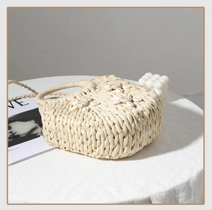 Dettaglio borsa in paglia con conchiglie decorative e motivi floreali all'uncinetto
