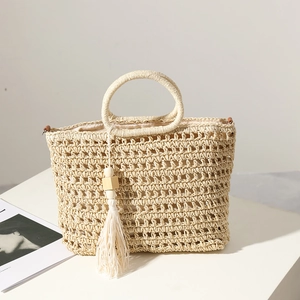Handmade hollow straw bag with round handles and tassel detail for summer beach