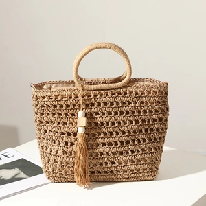 Handmade woven straw tote bag with tassel charm and hollow pattern for beach summer style