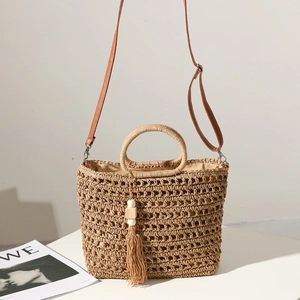 Handmade straw tote bag with hollow weave, brown leather strap and tassel detail