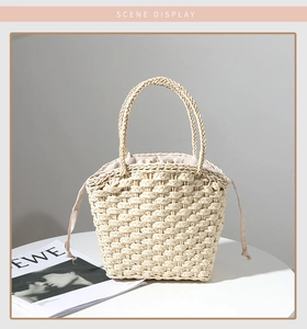 Detail of cross-weave straw handbag with interior drawstring liner on a white table