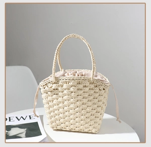 Detailed view of woven straw tote bag with drawstring lining and sturdy top handles