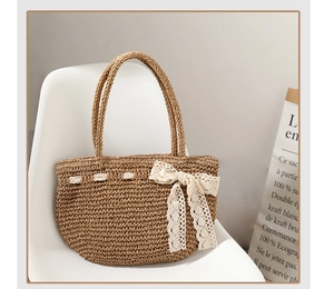 Détail du sac en paille tissé main avec nœud en dentelle crème sur une chaise