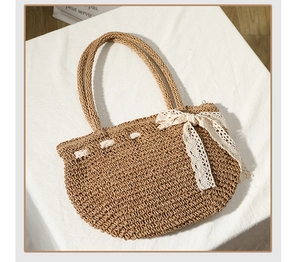 Détail du sac en paille avec nœud en dentelle blanche et deux poignées pour style de plage