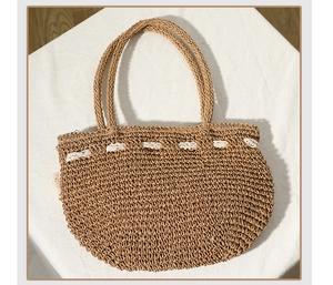 Détail d'un sac de plage tissé main avec bordure en dentelle blanche et doubles poignées