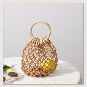 Detail einer handgefertigten Stroh-Strandtasche mit runden Holzgriffen und Netzstruktur