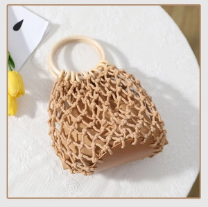 Detail der handgewebten Strohtasche mit Lederboden und Holzringgriffen für den Sommer