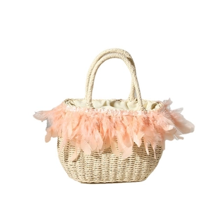 Handwoven straw tote bag with soft pink feathers and dual handles for beach vacation